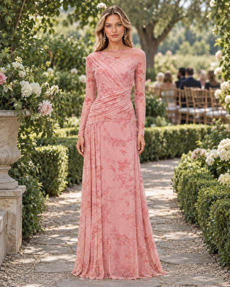 Wedding guest in a pink floral mesh long-sleeve maxi dress on a garden path.