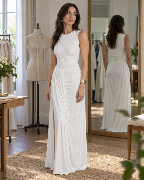 Woman checking the fit of a white ruched sleeveless gown in an alterations studio.